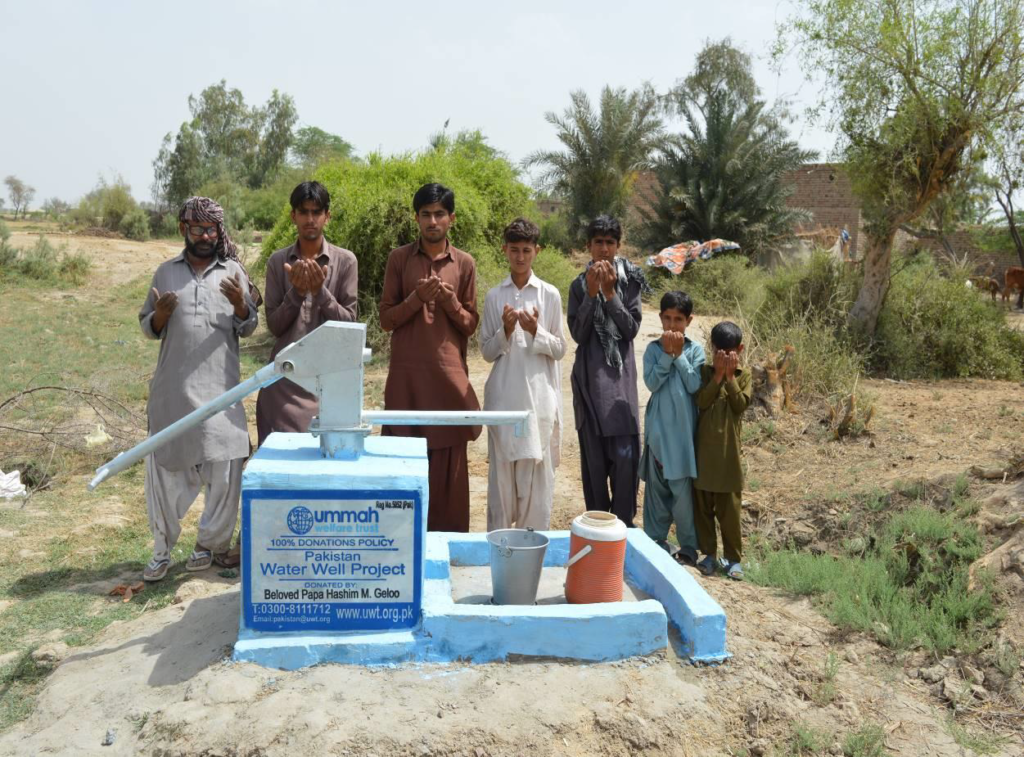 Boys gather around a newly installed water well in Pakistan, celebrating its completion as a vital resource for their community.